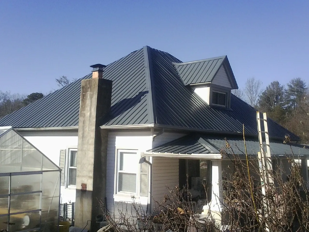 Dark blue standing seam metal roof on a white farmhouse with dormer — Slate & Tile Roof Repair by Roofing Brothers in Kents Store