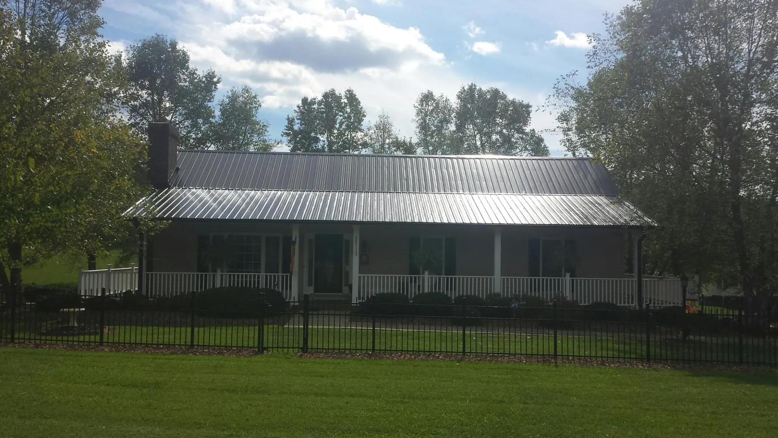 Gray metal roof on a brick ranch with a full width front porch — Gutter Guard Installation work by our crew in Kents Store