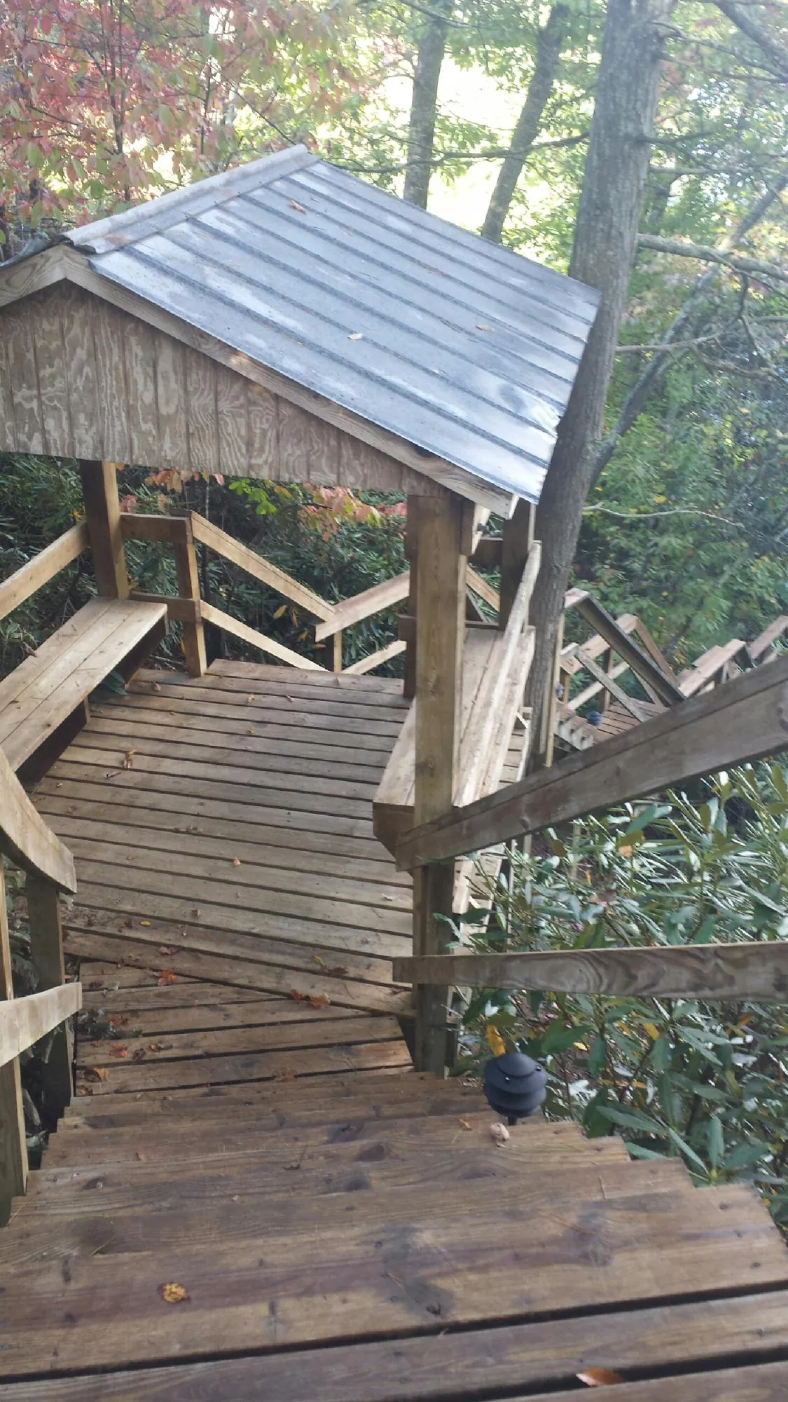 Metal roofed shelter over wooden steps on a wooded walkway — Skylight Repair & Installation work by our crew in Kents Store