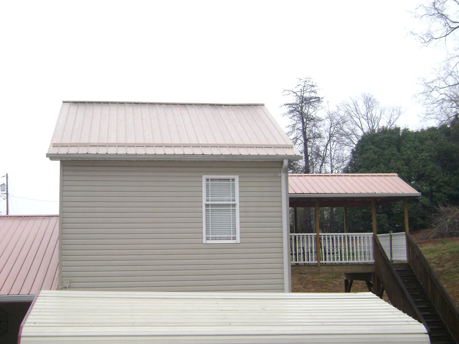 Tan metal roofs on a two story addition and attached porch, from a Roof Replacement job in Kents Store