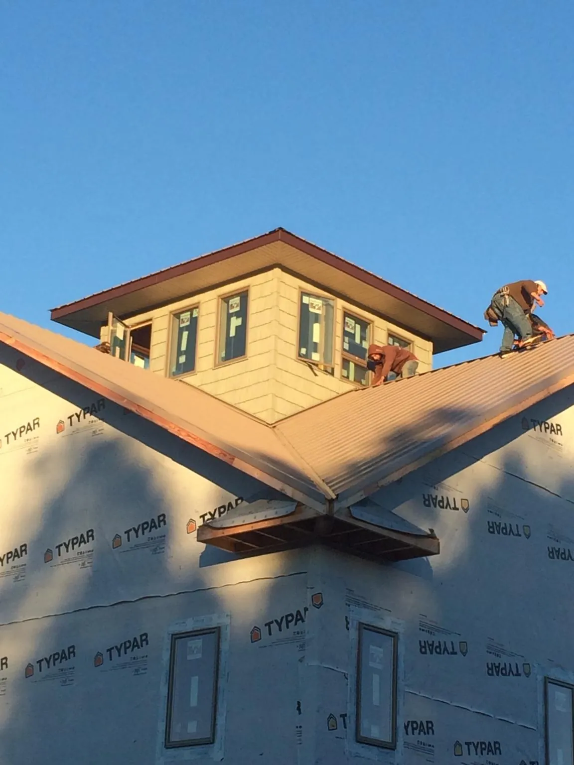 Roofers working around a rooftop cupola on a new metal roof at sunset — Roof Waterproofing in Kents Store by Roofing Brothers